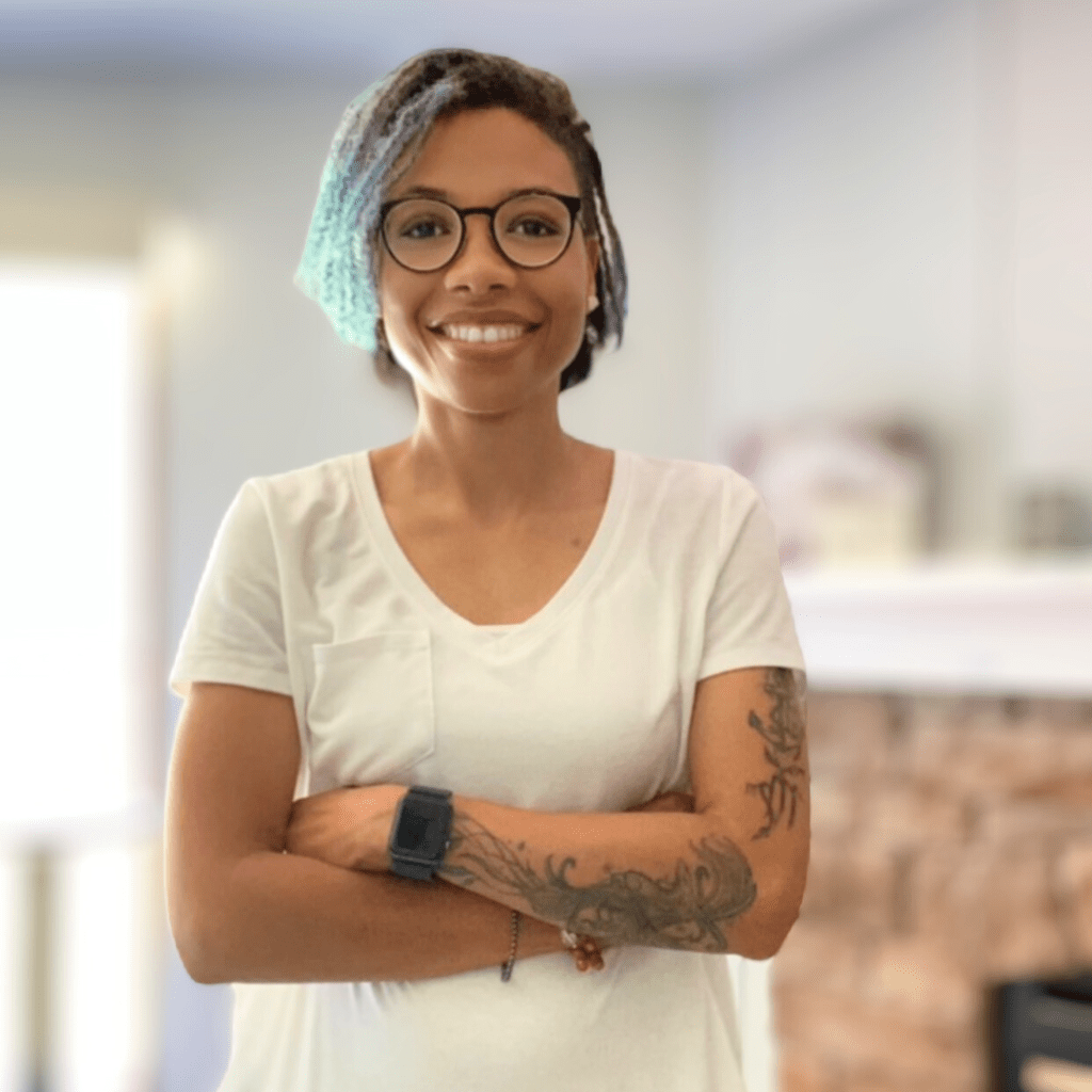 Evangela standing with her arms crossed and smiling.